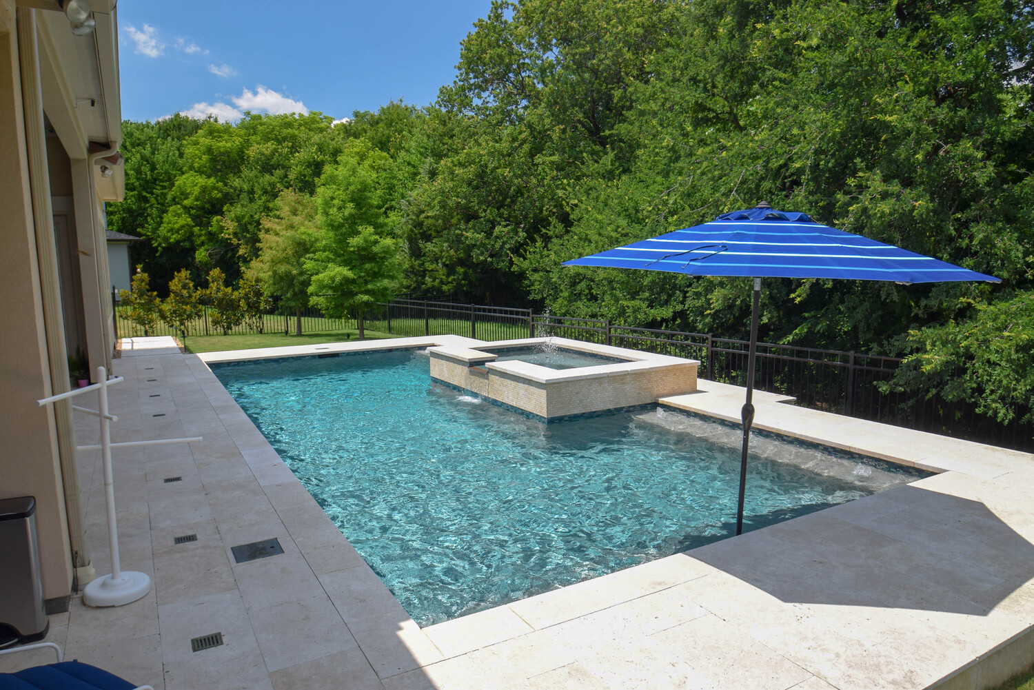 Backyard swimming pool with water feature and umbrella - Miller Pools